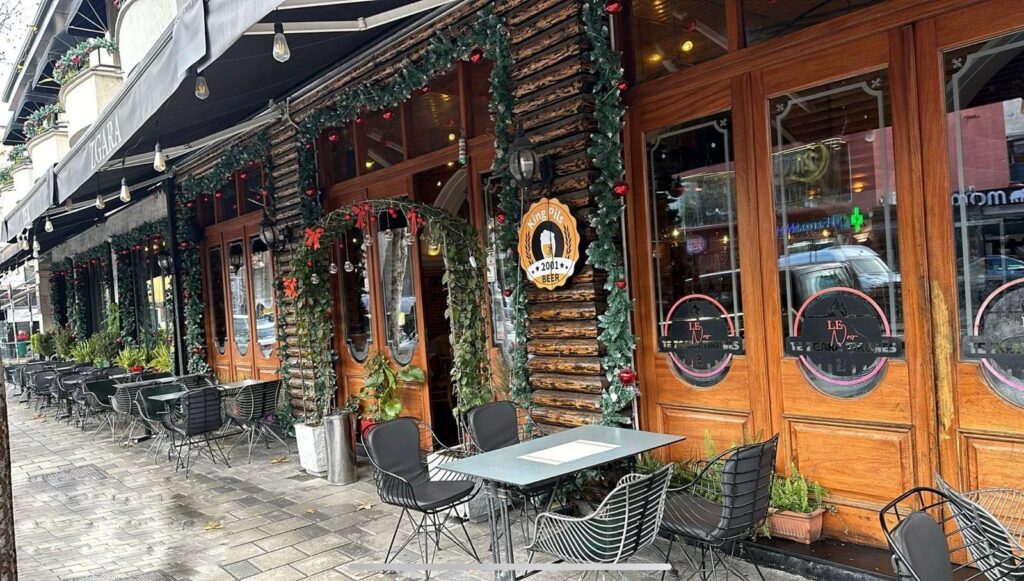 Sidewalk terrace tables outside the wooden facade of Zgara e Tironës 2 restaurant in Tirana