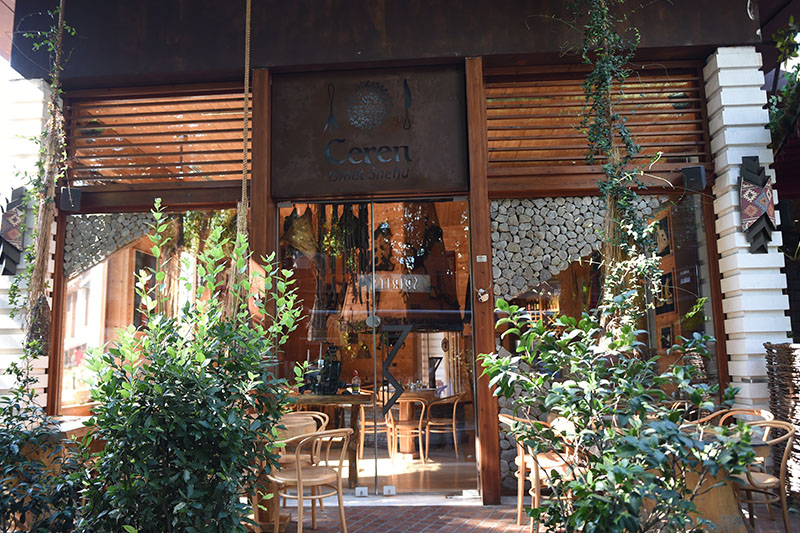 Wooden entrance of Ceren Ismet Shehu restaurant in Tirana framed by green plants